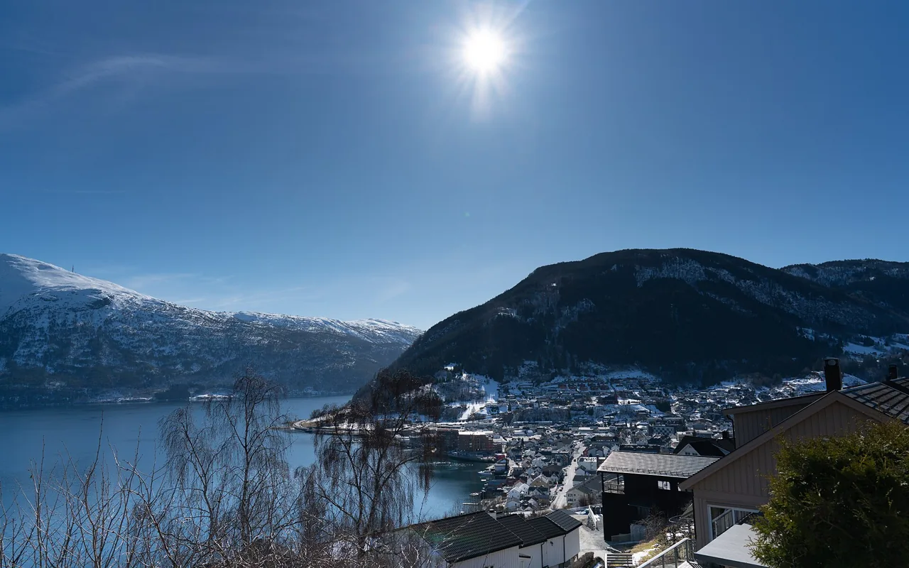 Sogndal sentrum ved fjorden i vårsol, med snø på fjellene